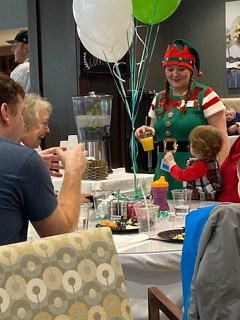 a woman dressed as an Elf holding a drink talking to a little girl at a party held by Traditions of Beavercreek