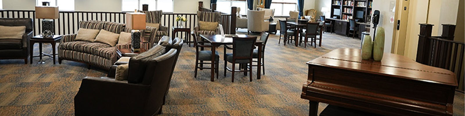 A community room with a piano and tables and chairs