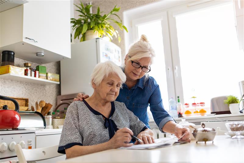 Female caregiver helping a female memory care resident with paperwork in Beavercreek, Ohio.