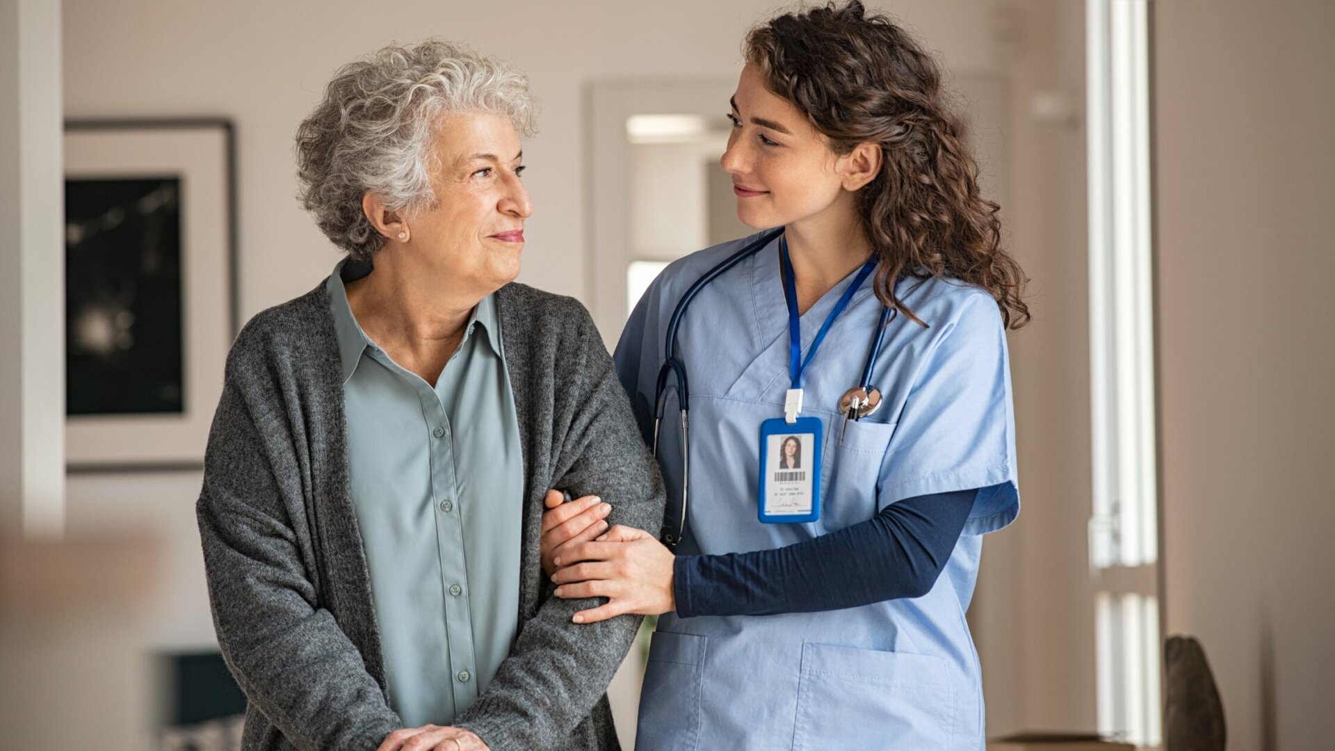Caregiver assisting female assisted living patient at Traditions of Beavercreek by holding her arm as they walk