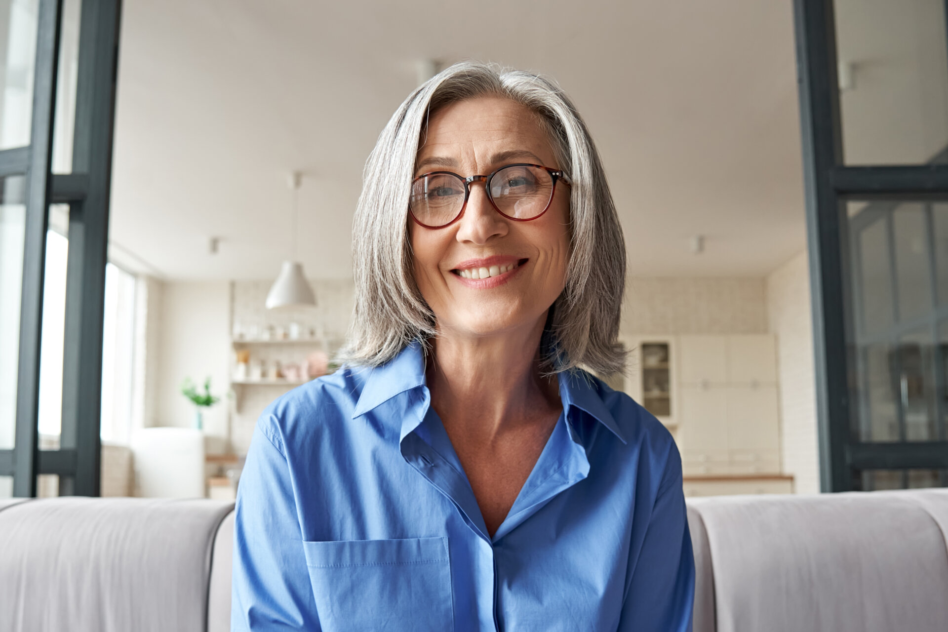 Senior female resident at Traditions of Beavercreek smiling while sitting in her senior apartment