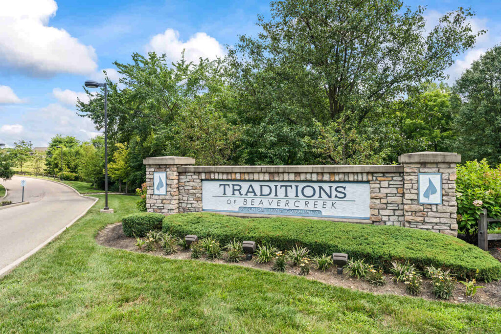 Sign to the right of a road with the text "Traditions of Beavercreek A Senior Living Community"