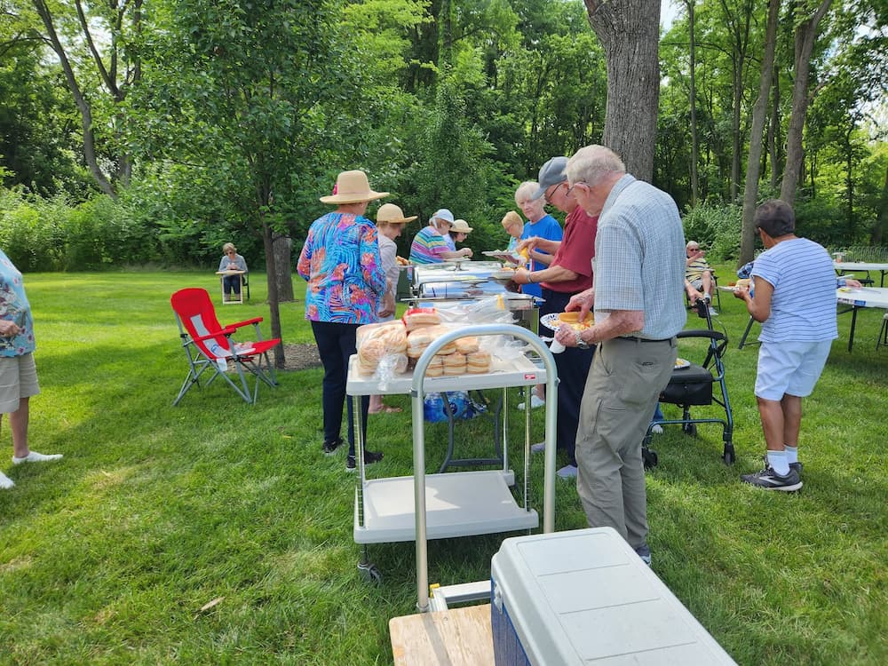 Residents enjoy a community cookout with freshly grilled food and outdoor dining at Traditions of Beavercreek.