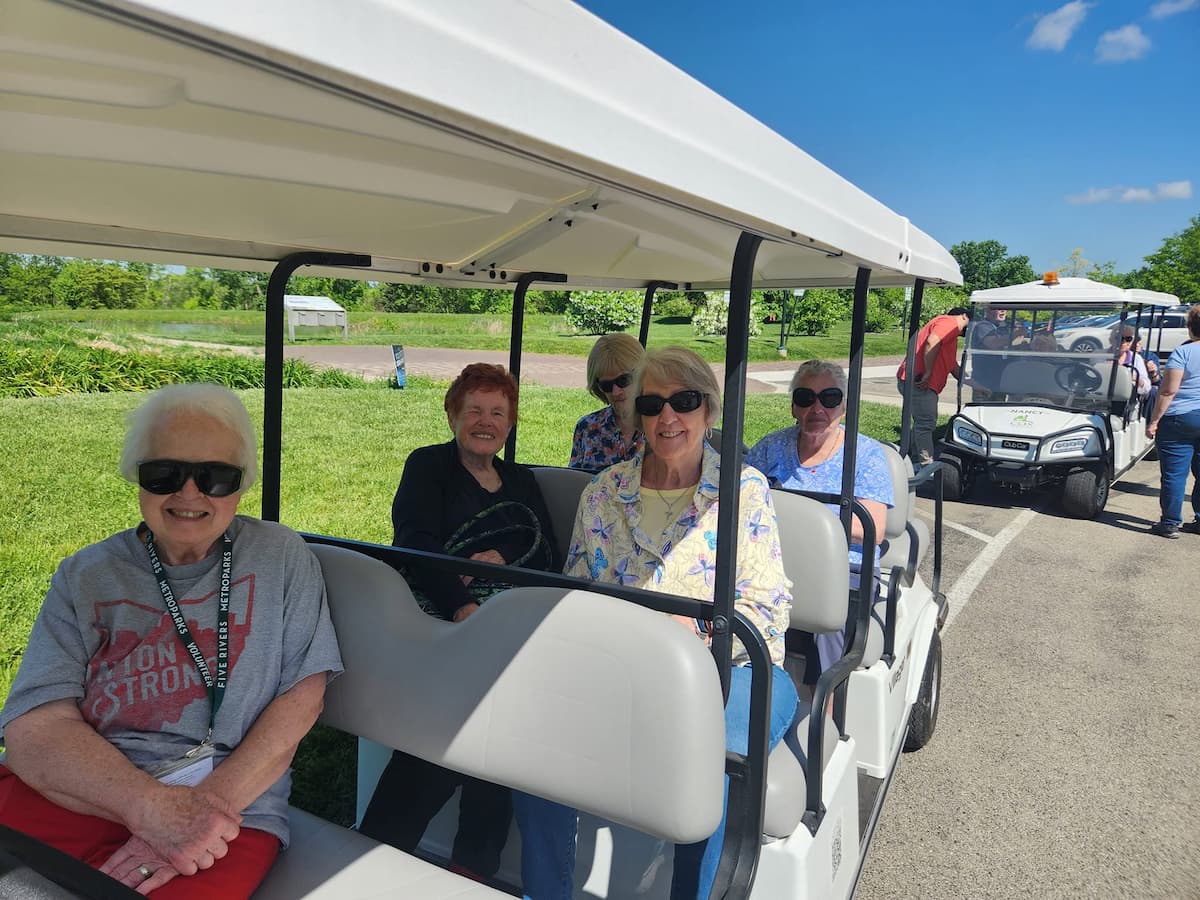 Residents ride golf carts during an outdoor community outing at Traditions of Beavercreek.