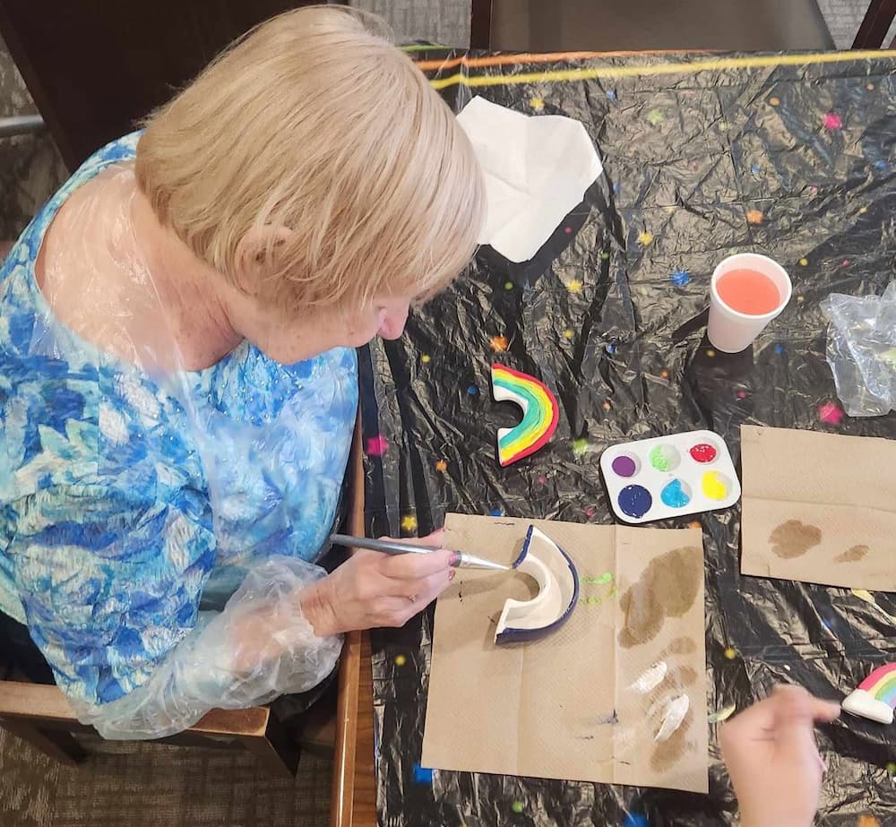 Resident paints a ceramic rainbow during a pottery painting activity at Traditions of Beavercreek.